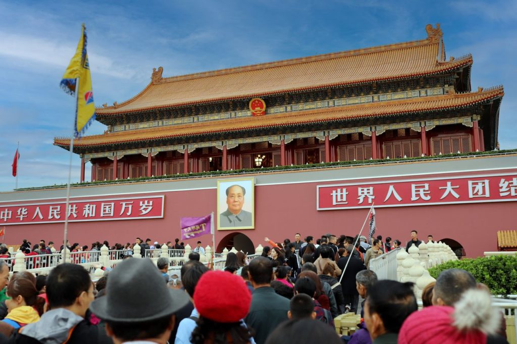 A large crowd gathers at the historic Tiananmen Gate in Beijing, China, showcasing Chinese architecture and culture.